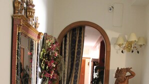 A hallway with a marble floor, a mirror with ornate gold trim, a statue, and a vase with flowers. - Selene Policlinico di Catania (Gravina di Catania)