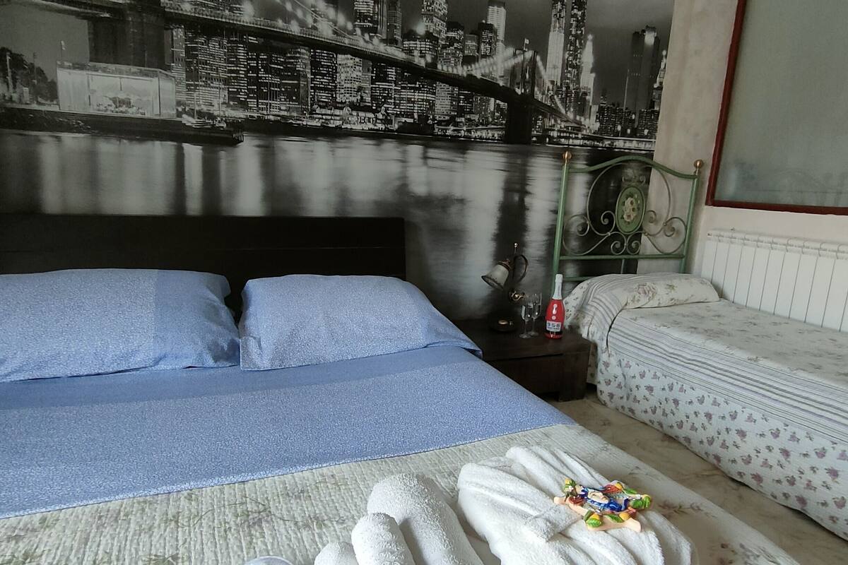 Une chambre d’hôtel avec un lit, un canapé et une fresque représentant un paysage urbain sur le mur.