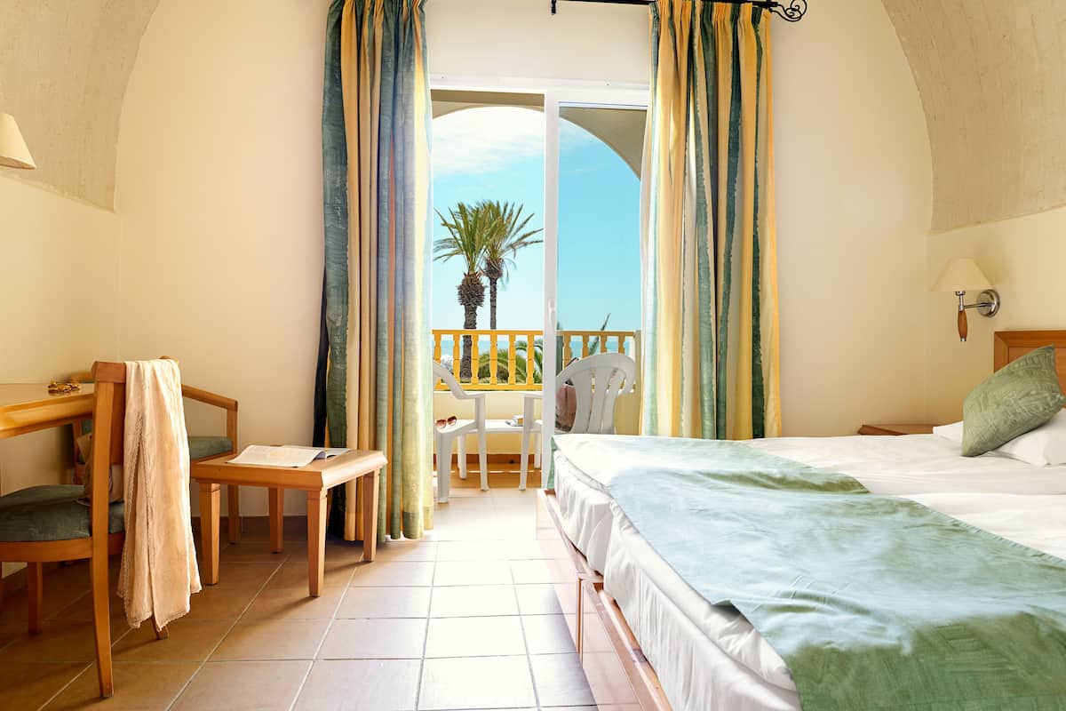 Une chambre avec un balcon, un bureau et une chaise.