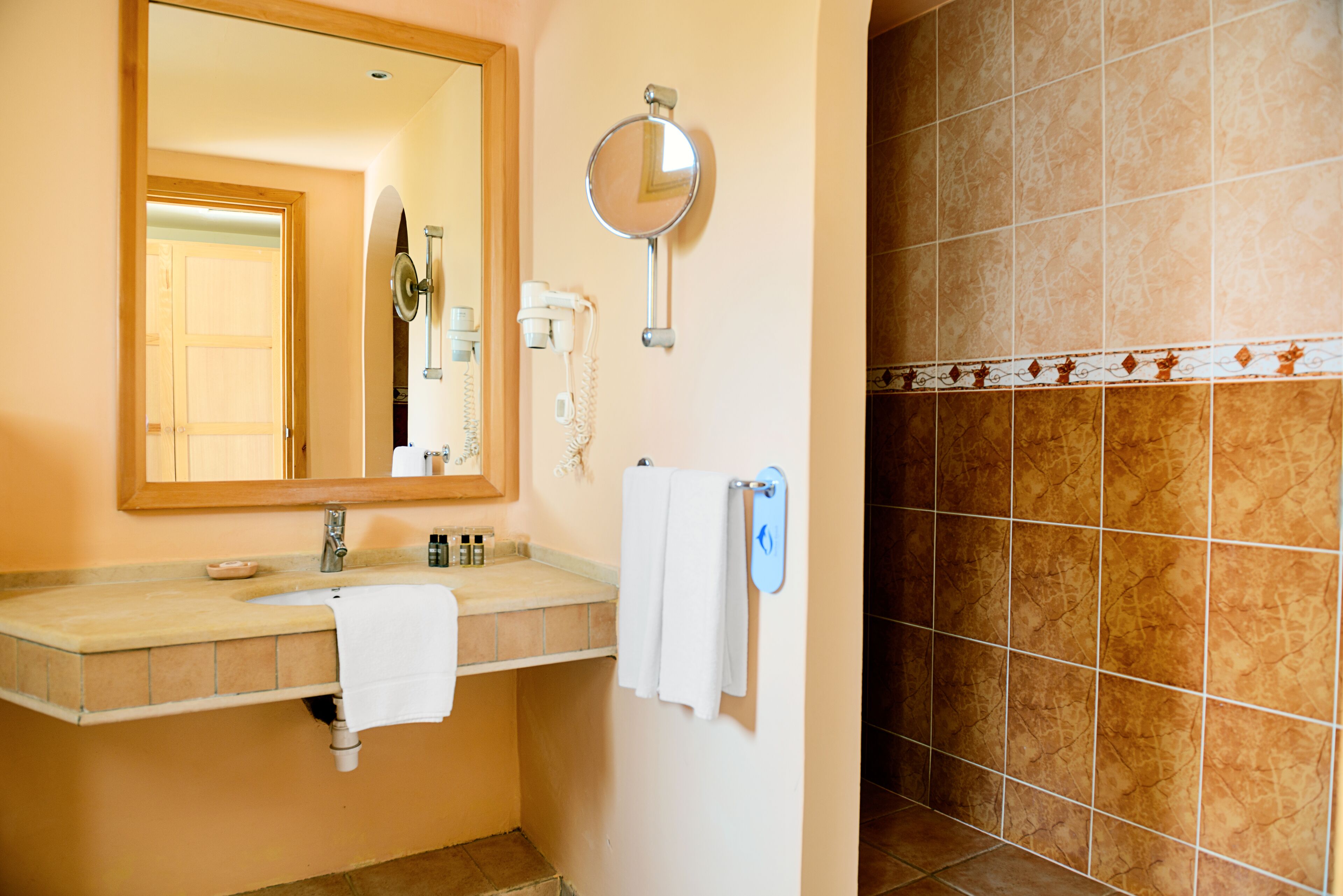Une salle de bain équipée d’un lavabo, d’un miroir, d’un porte-serviettes et d’une zone douche.