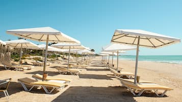 Een privéstrand, ligstoelen aan het strand, parasols, strandlakens