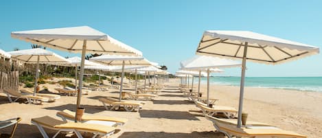 Een privéstrand, ligstoelen aan het strand, parasols, strandlakens