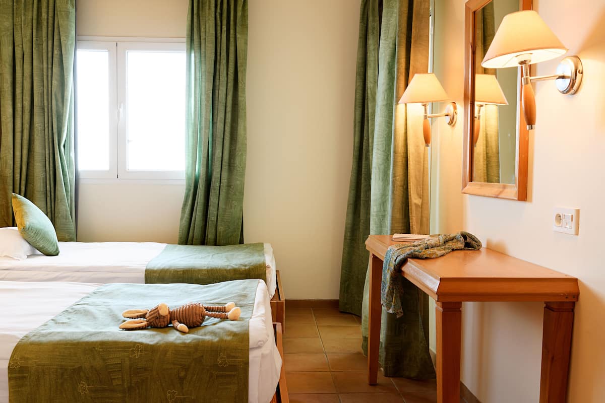 Une chambre d’hôtel avec deux lits, une table en bois et un miroir.