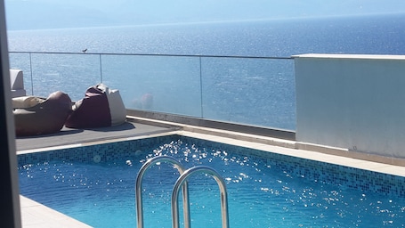 Una piscina al aire libre de temporada, sillones reclinables de piscina