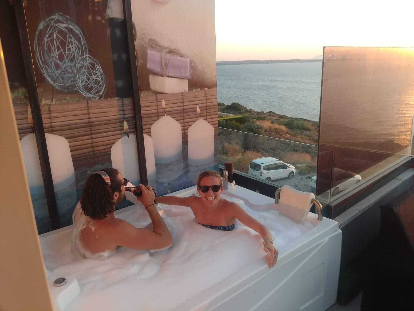 A room with a bathtub and a large window overlooking the sea.