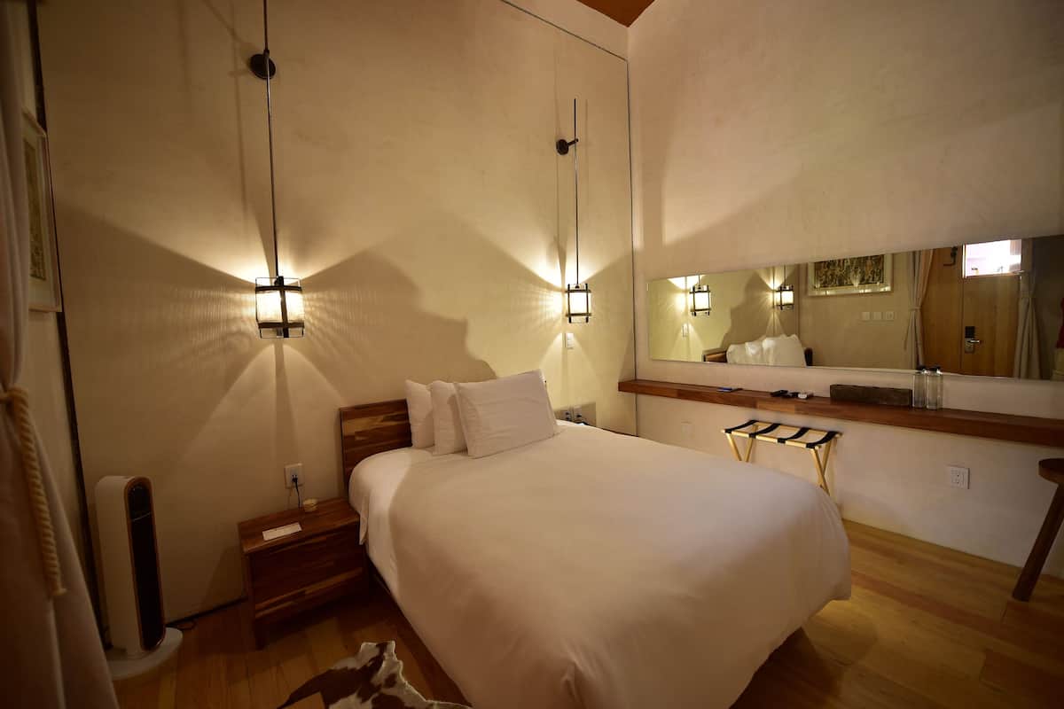 A bedroom with a large bed, bedside tables, a mirror, and a heater.