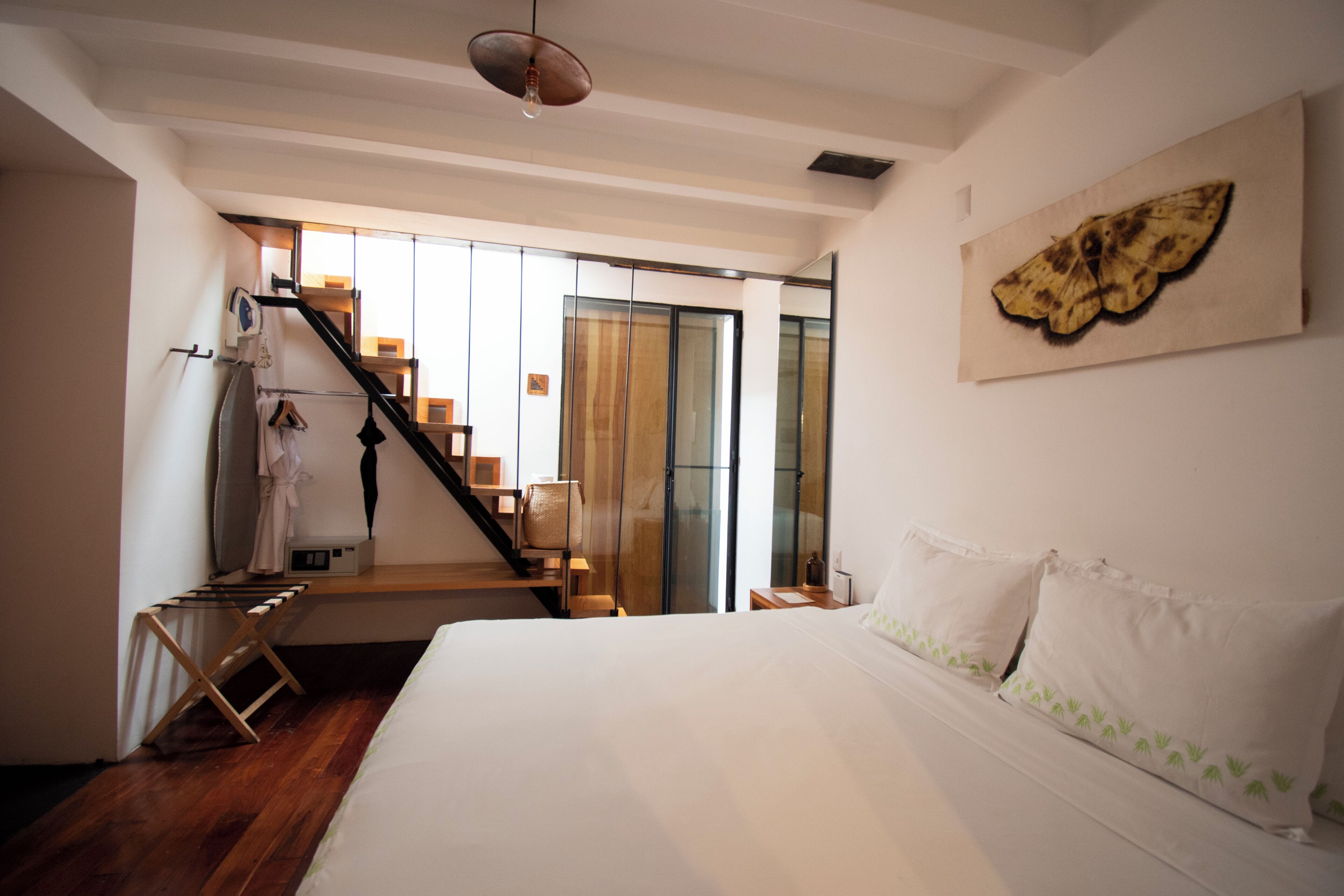 Ein Schlafzimmer mit einem großen Bett, einer Holztreppe und Blick ins Freie.