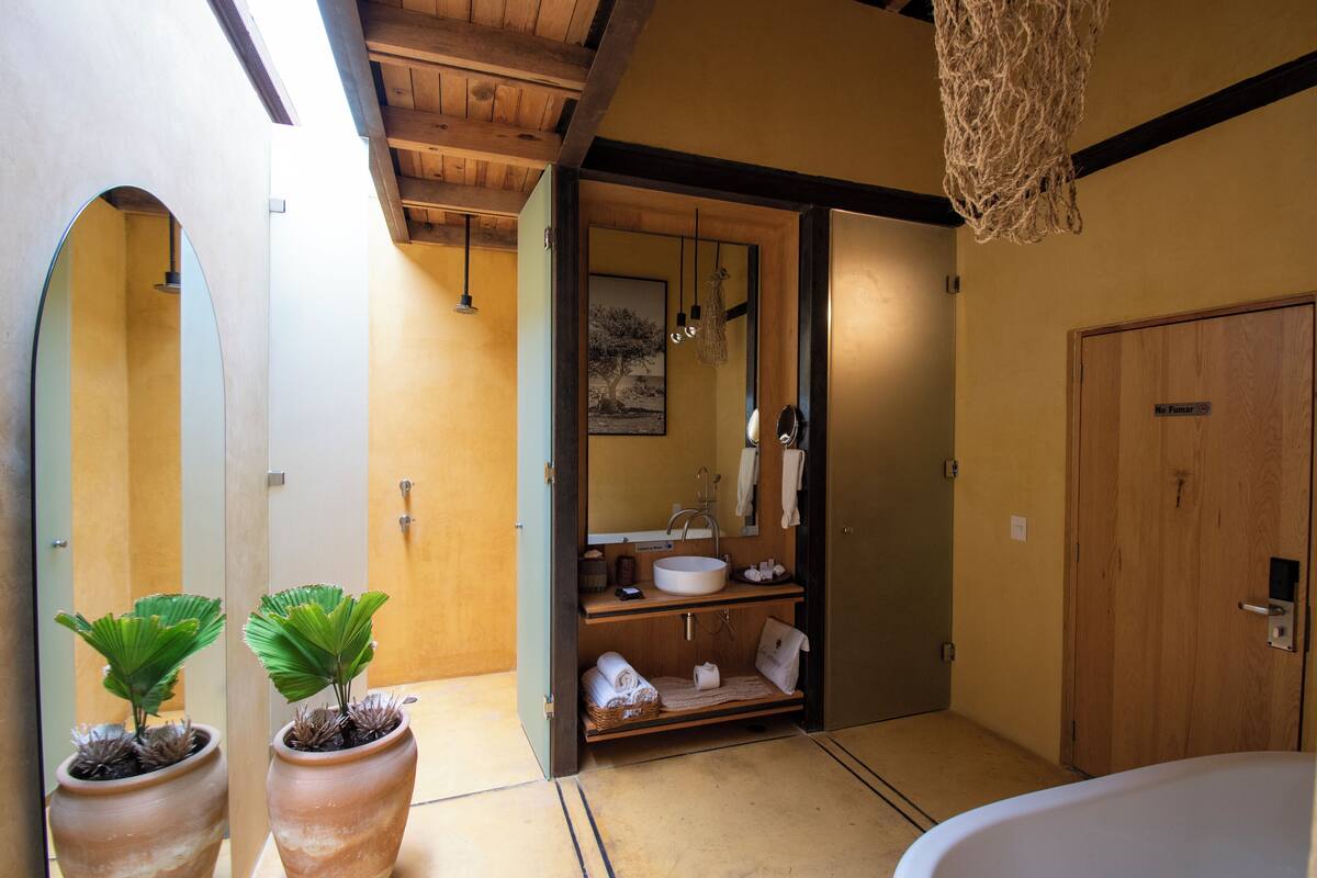 A bathroom with a large mirror, wooden shelves, a sink, and two potted plants.