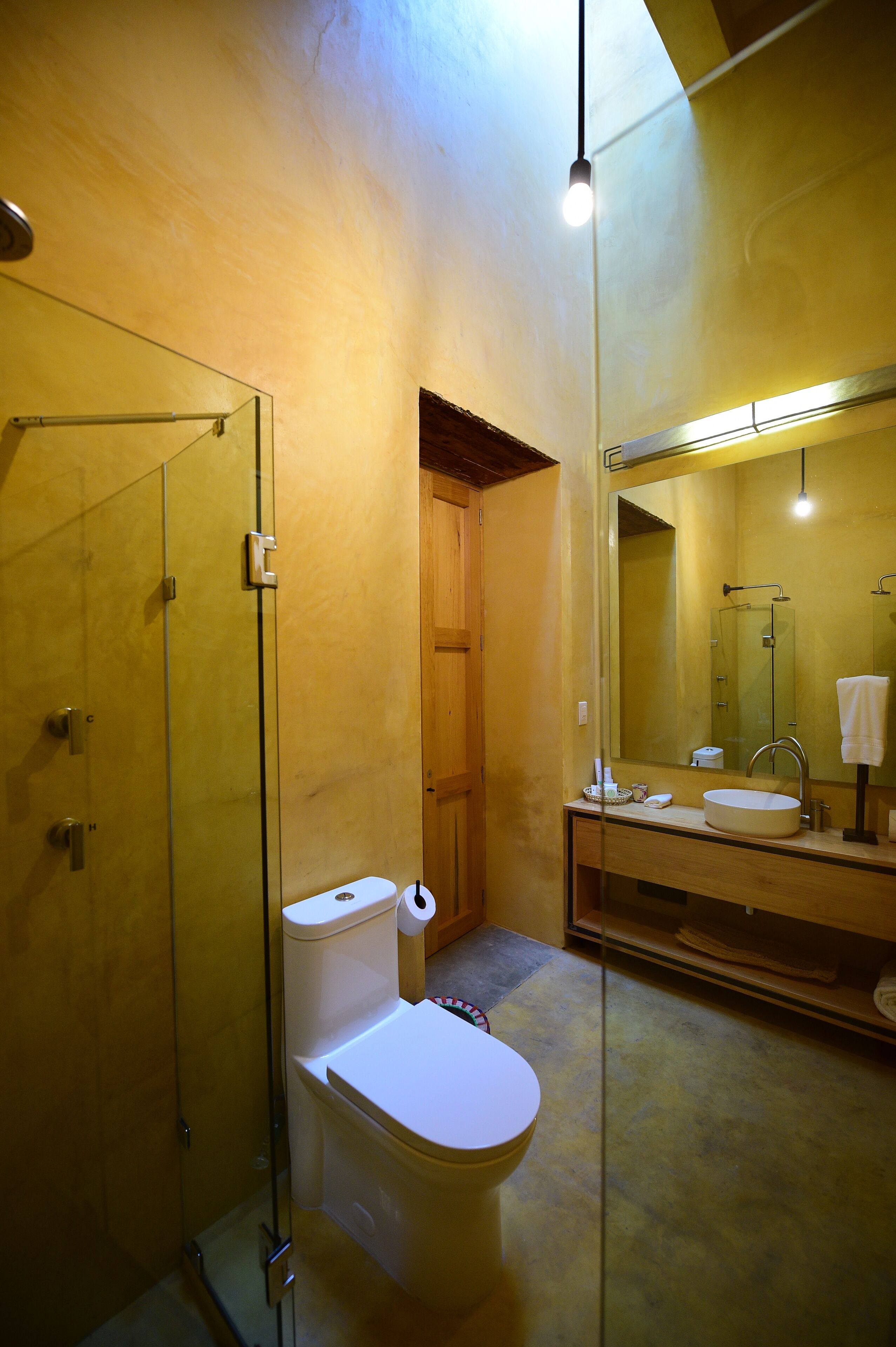 Une salle de bain moderne avec une douche à parois de verre, des toilettes blanches et un grand miroir au-dessus du lavabo.