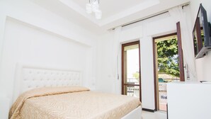 Ein Hotelzimmer mit einem großen Bett, einem Fernseher und einem Balkon mit Ausblick ins Freie.