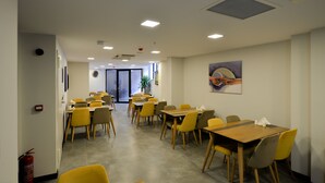 A spacious dining area with multiple tables and chairs, a fire extinguisher, and a door leading to another room. - Zeytindali Hotel (Trabzon)