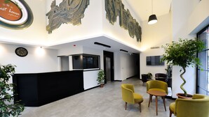 A modern hotel lobby with a reception desk, seating area, and decorative wall art. - Zeytindali Hotel (Trabzon)