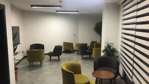 A modern interior with a seating area featuring yellow and dark-colored chairs, a small round table, and a striped wall. - Zeytindali Hotel (Trabzon)