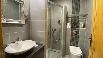 A modern bathroom with a large sink, a glass-enclosed shower, and a toilet.
