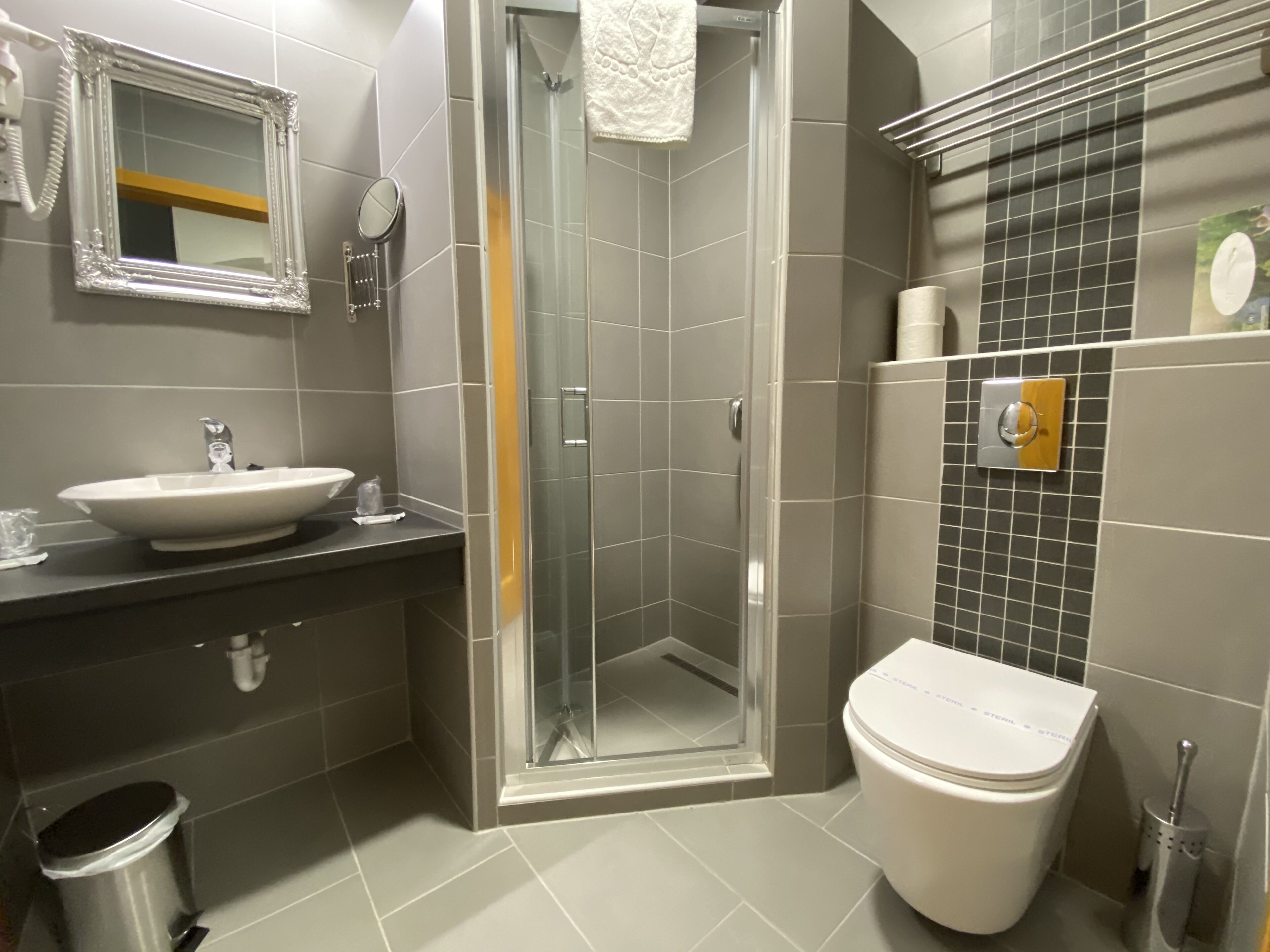 Un baño moderno con lavamanos, espejo, inodoro y ducha.