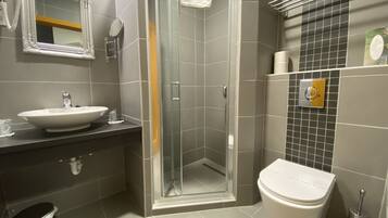 Un baño moderno con lavamanos, espejo, inodoro y ducha.