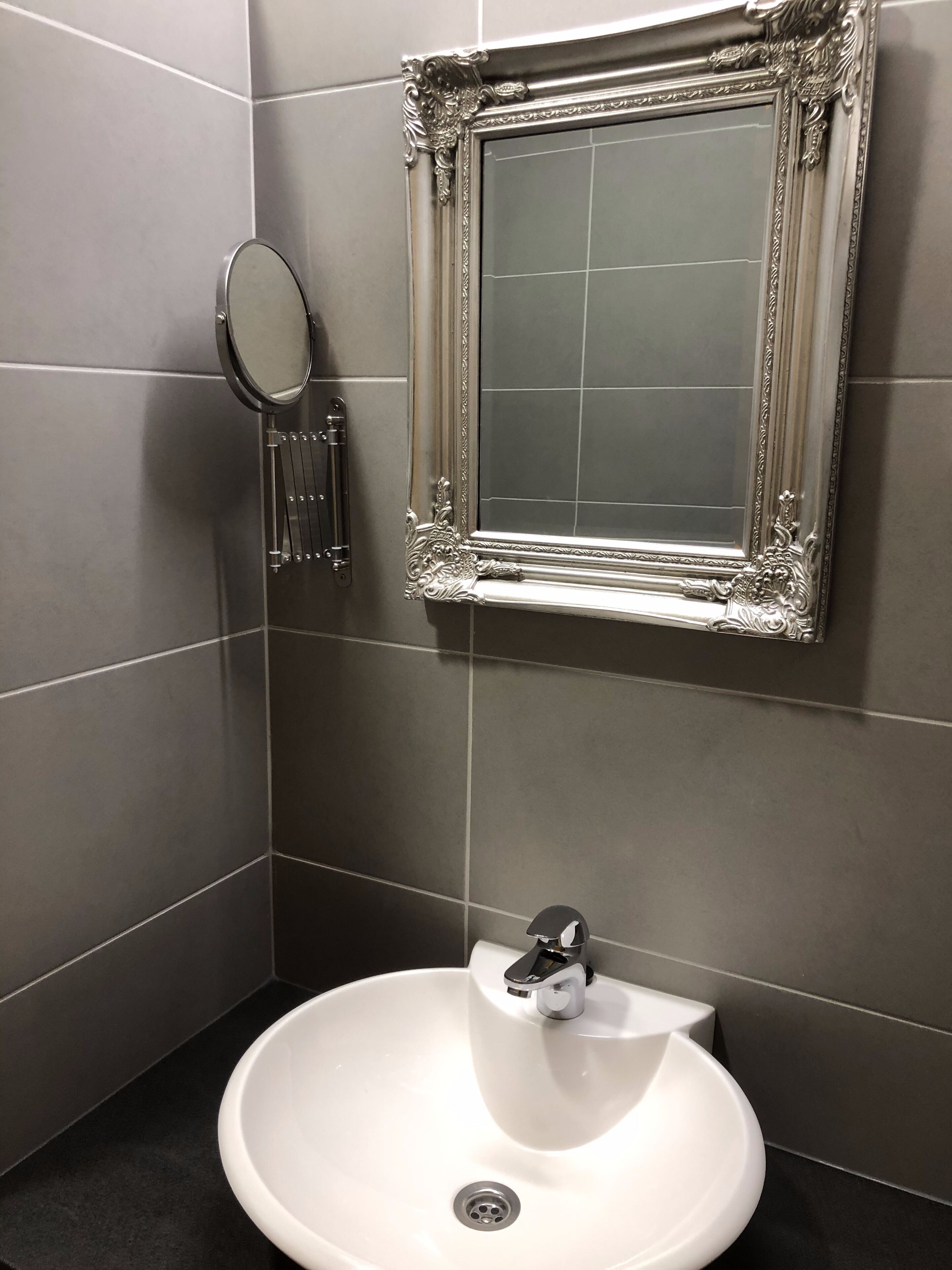 Un baño con un lavamanos blanco, un espejo y un marco decorativo en la pared.