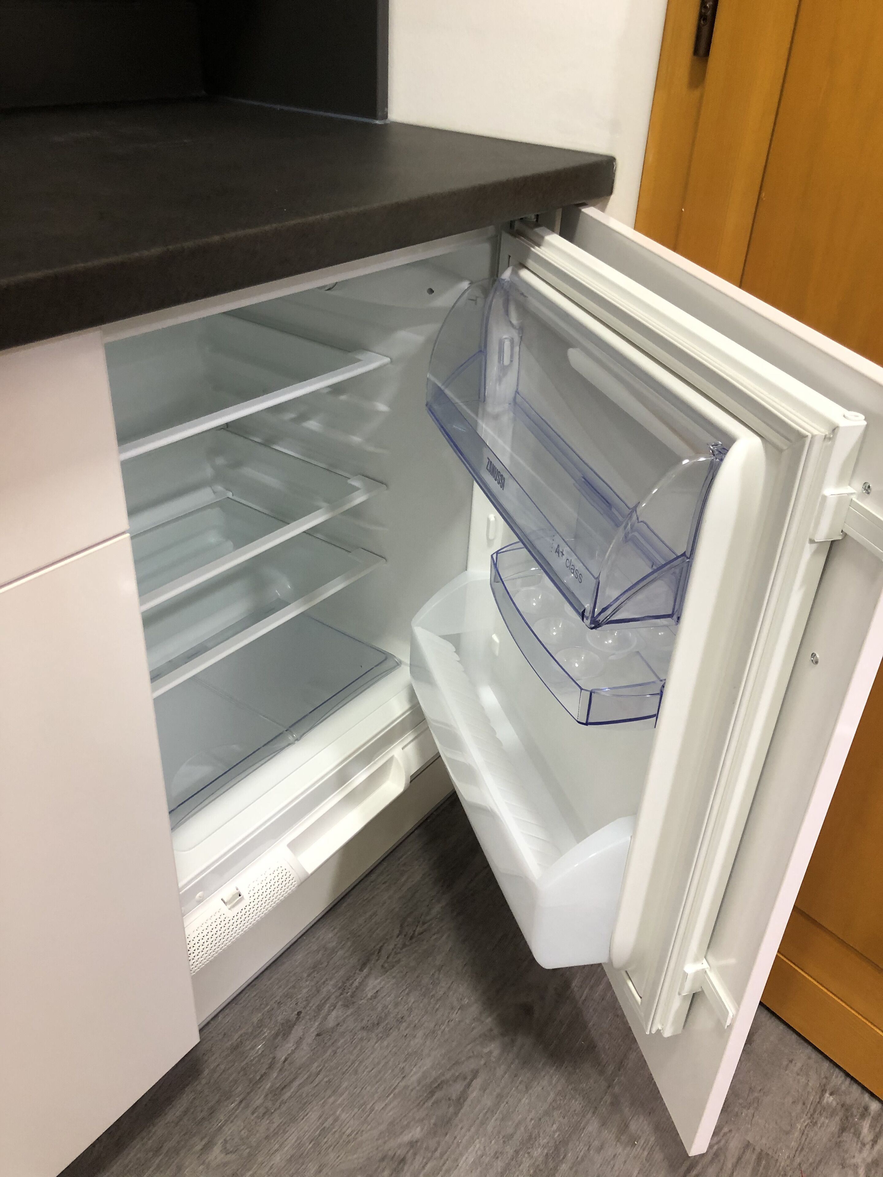 An open refrigerator with transparent shelves and a white interior.