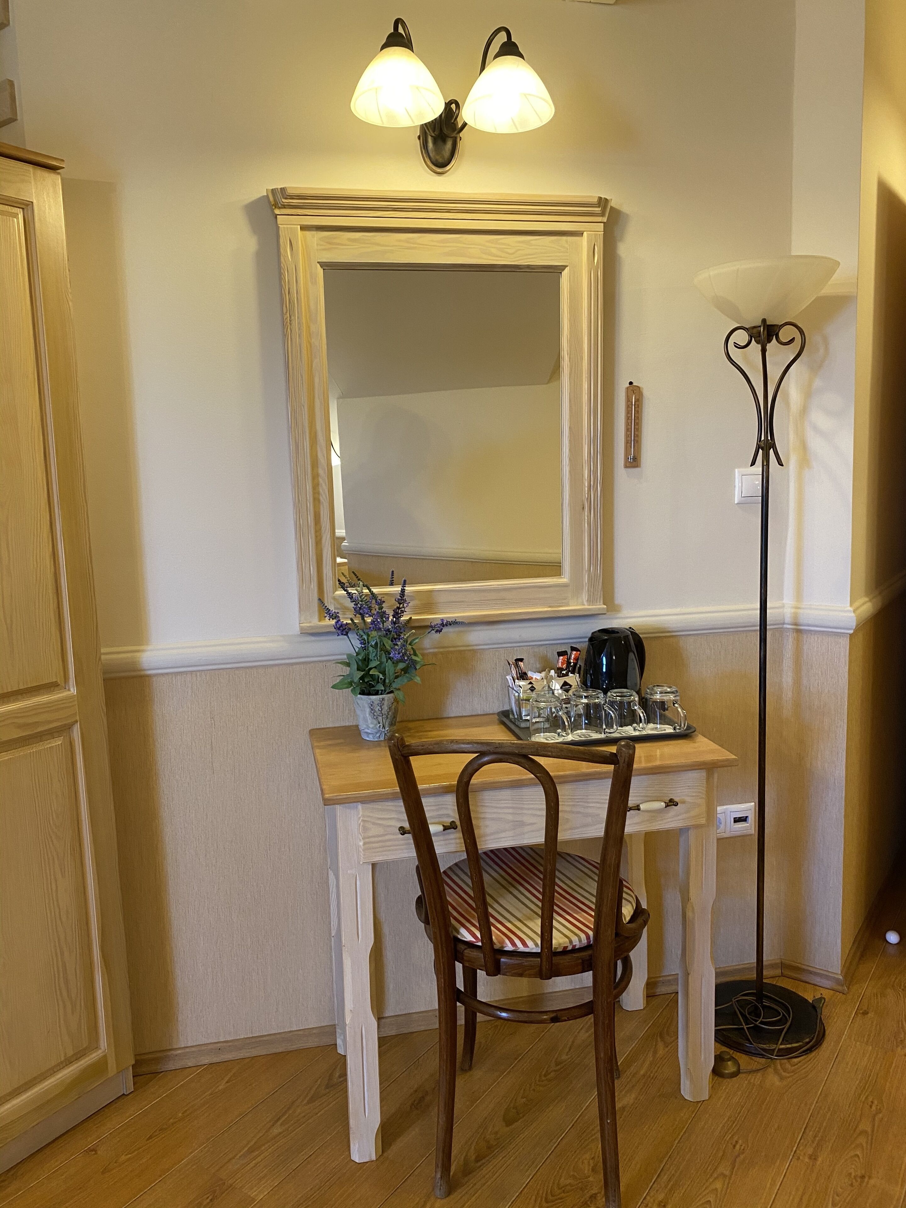 A wooden desk with a mirror, a potted plant, and a coffee maker.