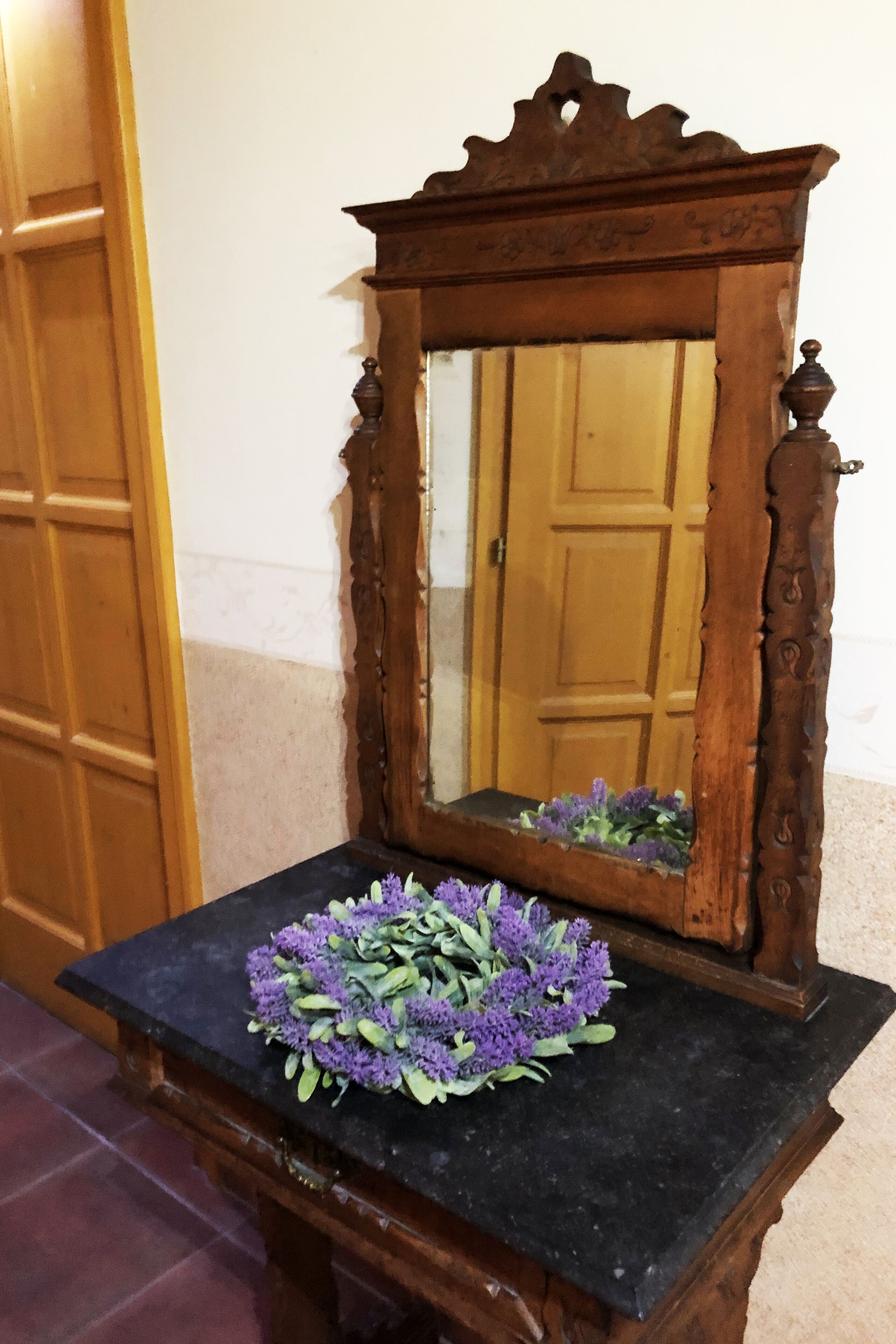 Um espelho de madeira com um arranjo floral sobre uma mesa de mármore preto.