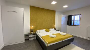 A modern bedroom with a large bed, bedside tables, a wardrobe, and a window with curtains.
