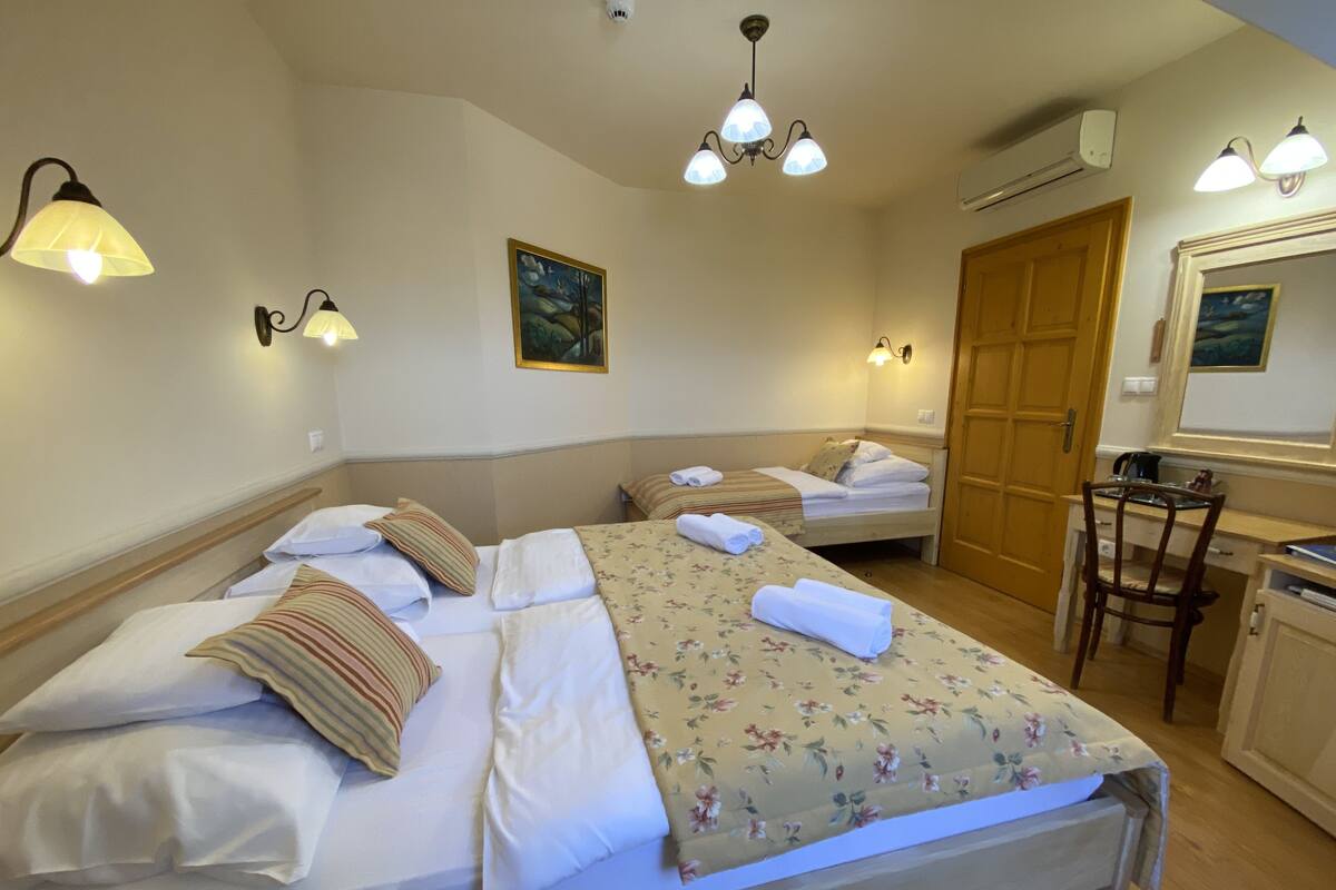 Una habitación de hotel con dos camas, un escritorio de madera, una silla y un cuadro en la pared.
