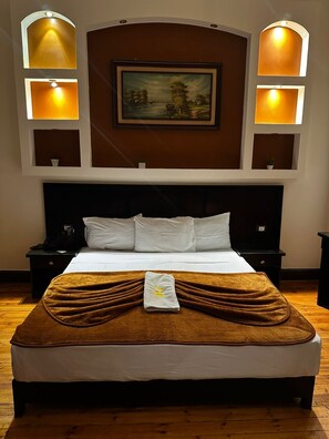 A hotel room with a large bed, a painting above the headboard, and wall-mounted sconces. - Paradise Boutique Hotel (Cairo)