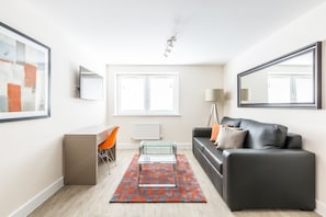 A modern living room with a glass coffee table, a black leather sofa, and a red patterned rug. - Solstice House by House of Fisher (Farnborough)