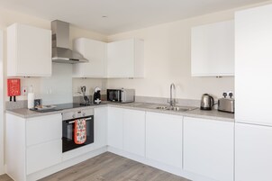 Una cocina moderna con armarios blancos, electrodomésticos de acero inoxidable y piso de madera.