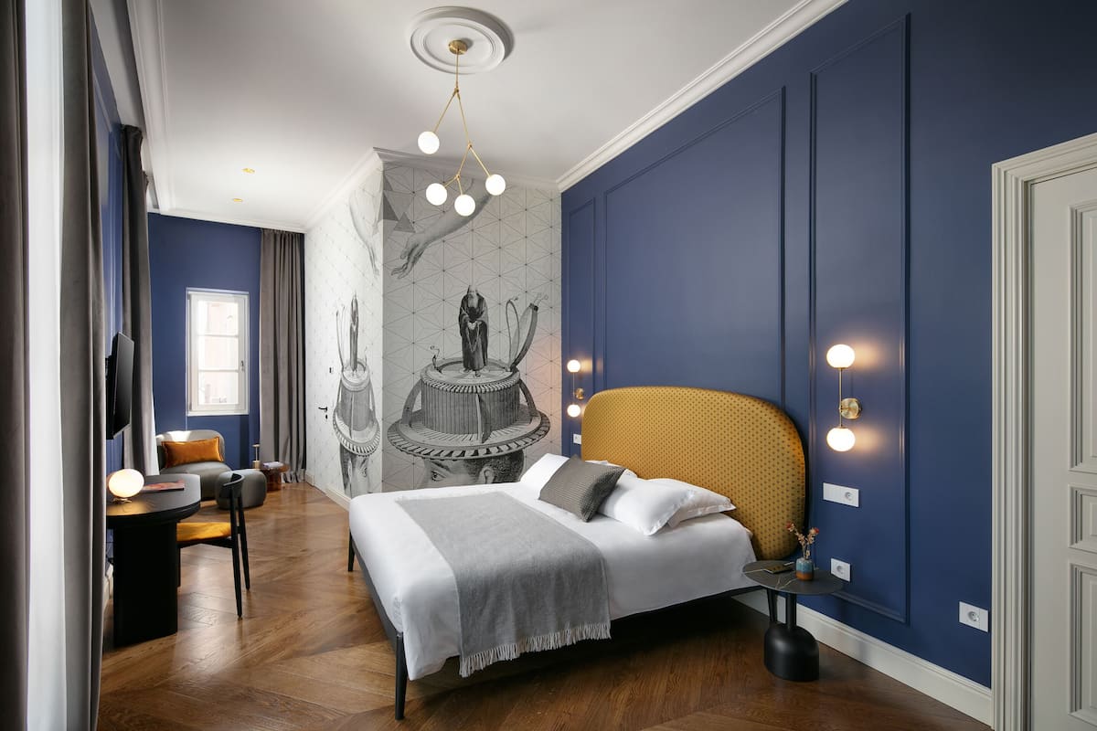 Une chambre à coucher comprenant un lit, un bureau, une chaise et un mur orné d’un motif géométrique.