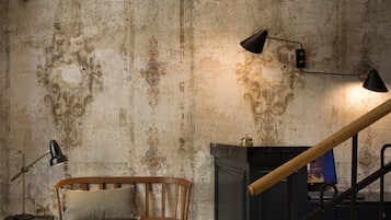 A rustic room with a wooden bench, a desk with a lamp, and a staircase.