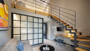 A modern living room with a sofa, coffee table, and a staircase with a TV. - Almayer Art & Heritage Adults Only Hotel & Dépendance Rooms (Zadar)