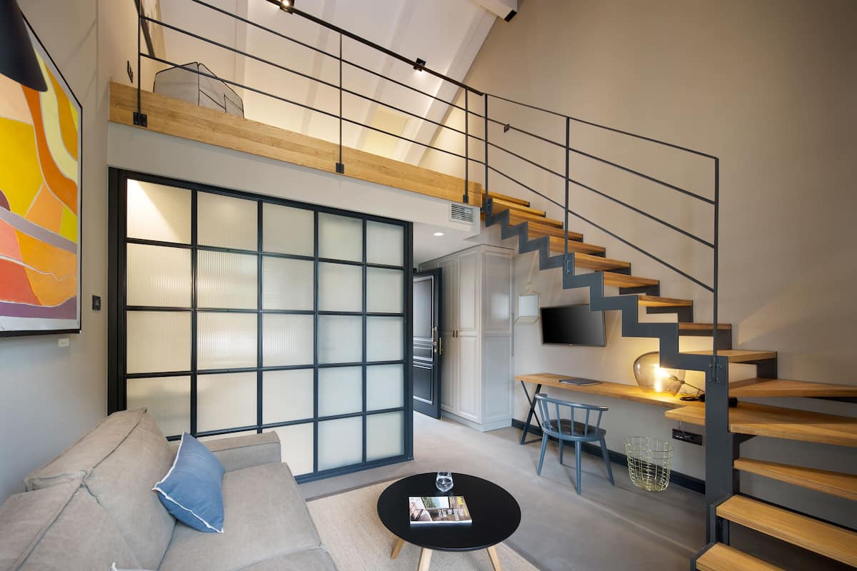 Un salon moderne avec un canapé, une table basse et un escalier, le tout agrémenté d’un téléviseur.