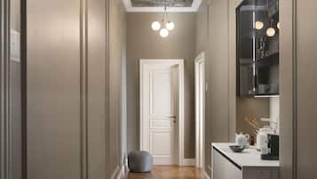 A hallway with a wooden floor, a white door, and a kitchen area with a marble countertop.
