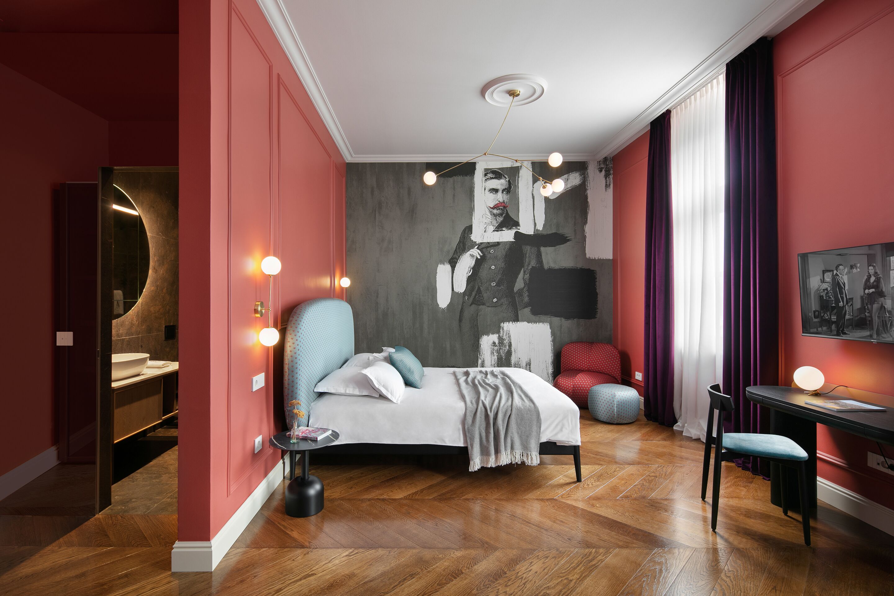 A modern bedroom with a bed, a desk, and a large abstract painting on the wall.