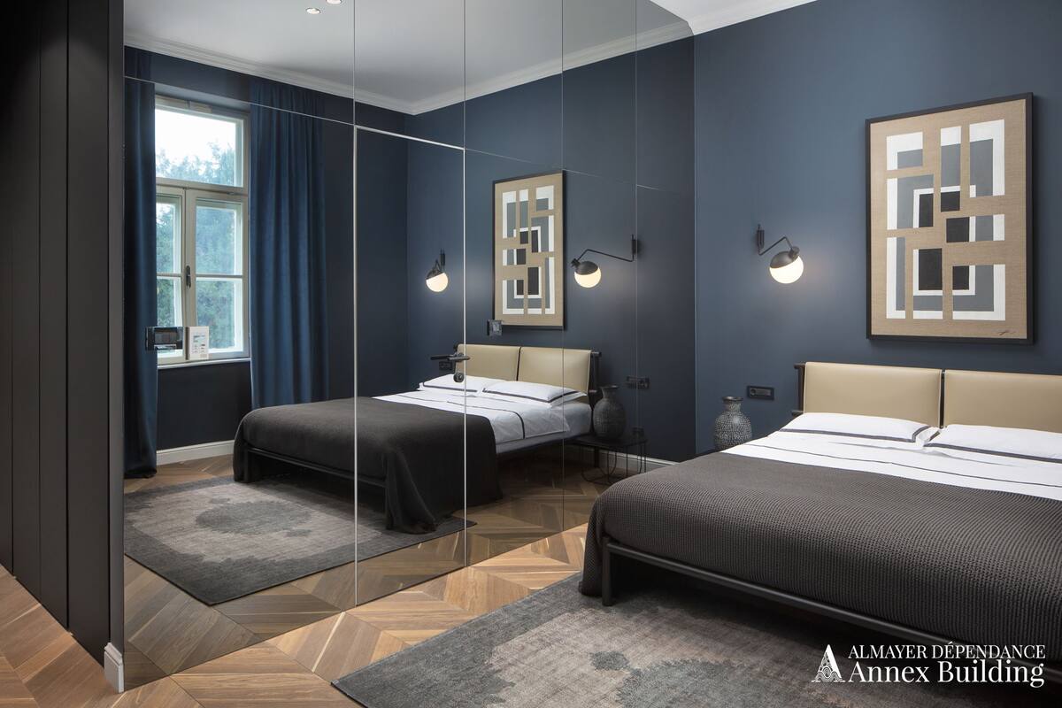 Une chambre moderne avec deux lits, un grand miroir et une vue sur l’extérieur.