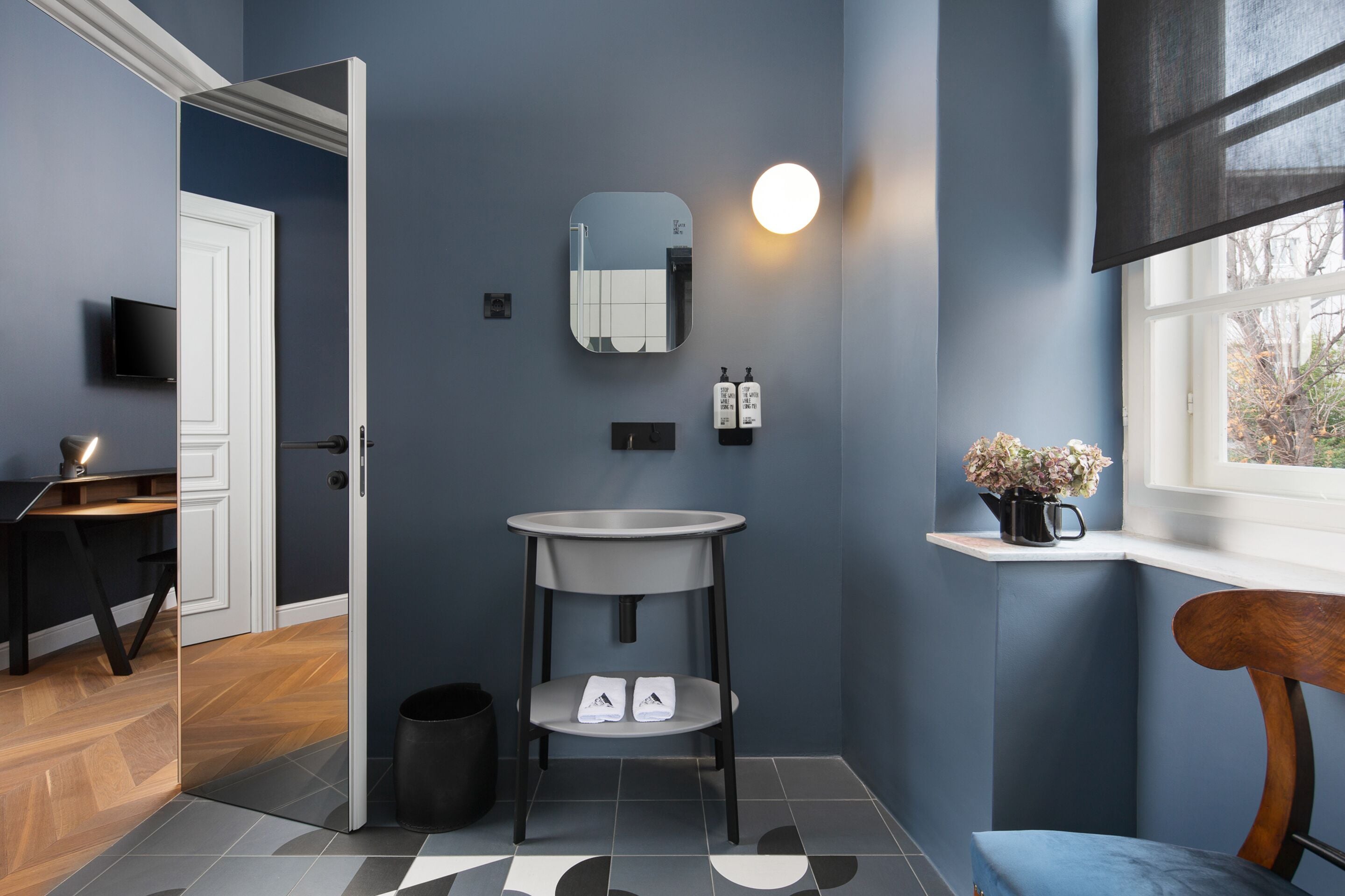 A modern bathroom with a sink, mirror, and toiletries.