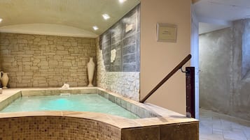 Un espace spa doté d’un jacuzzi, de murs en pierre et d’un sol carrelé.