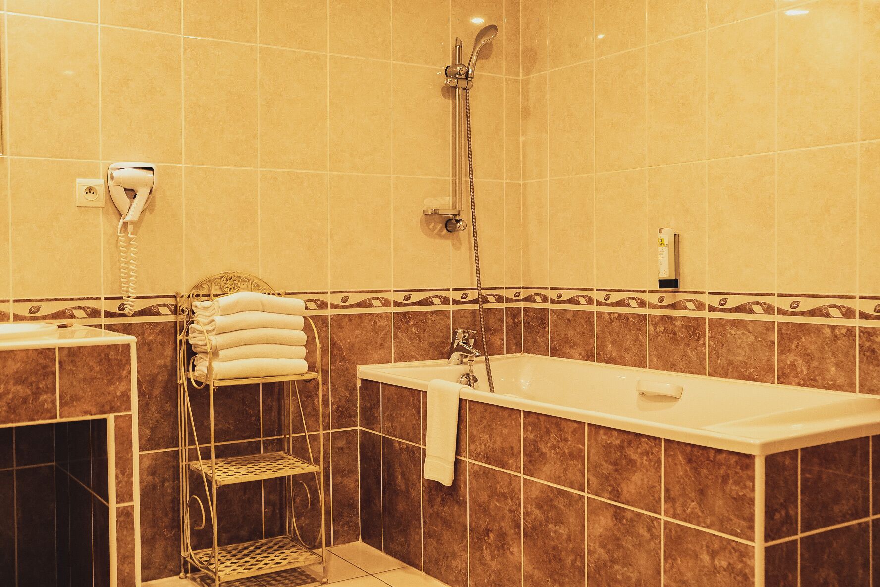 Un baño con bañera, ducha, toallero y estante.