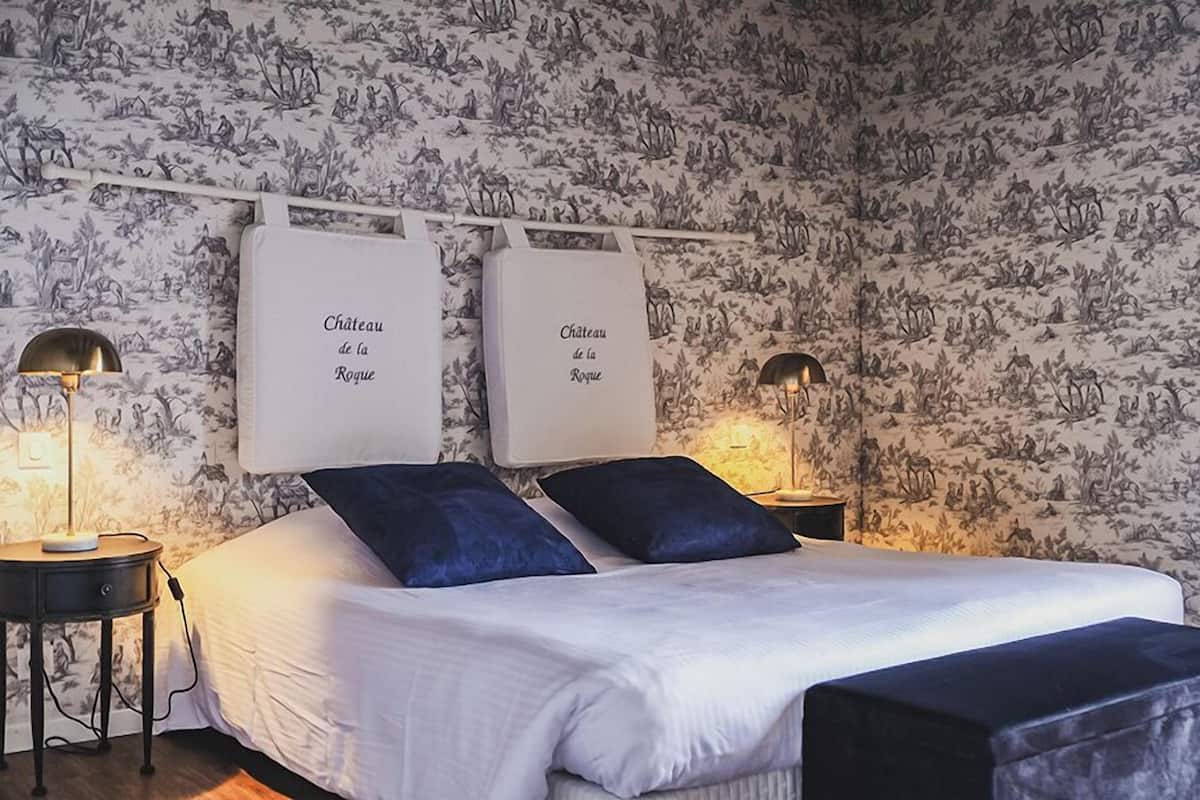 A bedroom with a bed, two bedside tables, and two wall-mounted signs reading "Chateau de la Rognue".