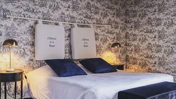 A bedroom with a bed, two bedside tables, and two wall-mounted signs reading "Chateau de la Rognue".