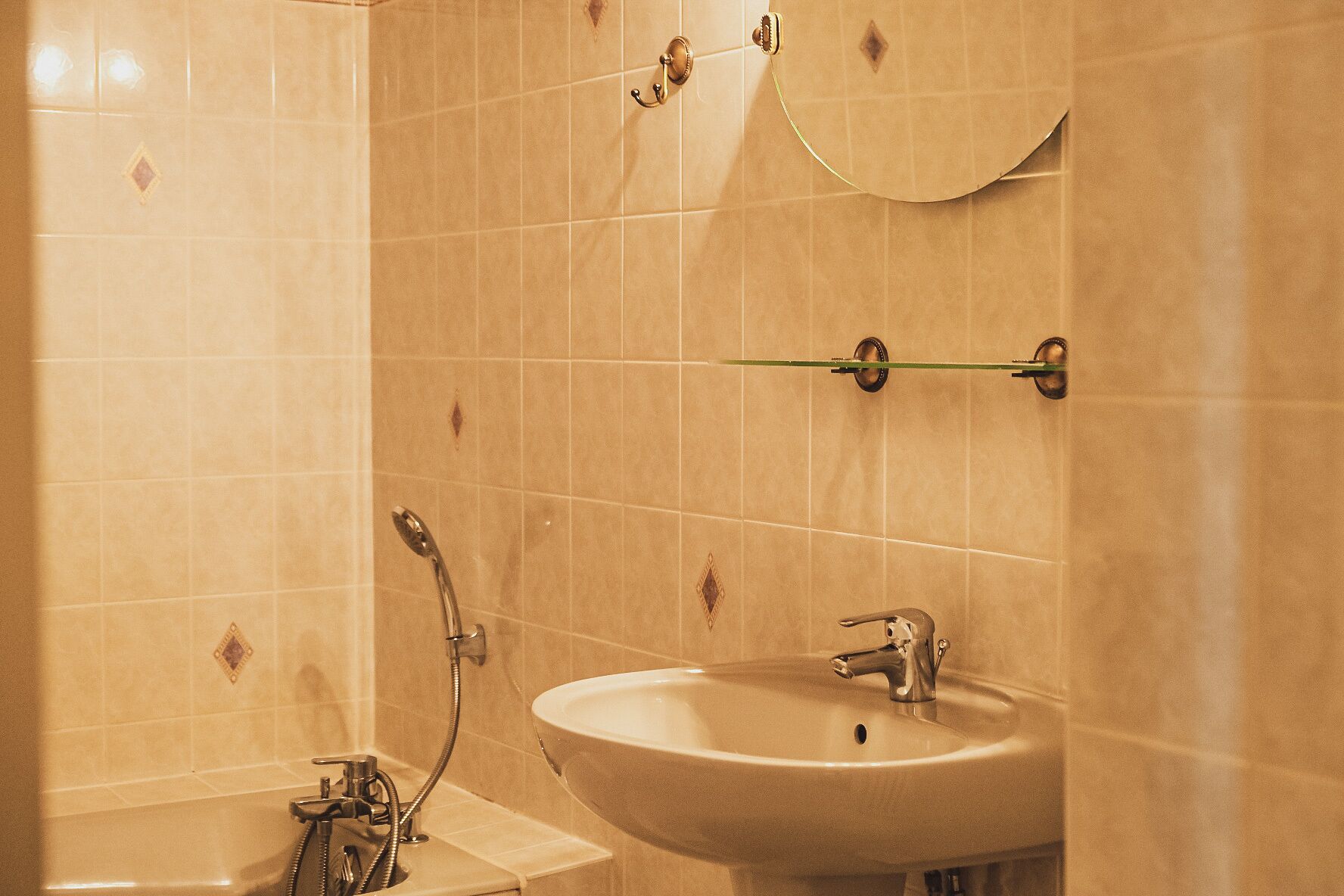 Een badkamer met een wastafel, spiegel en douche.