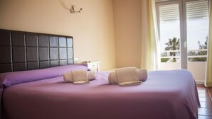 Een hotelkamer met een groot bed, een nachtkastje en uitzicht op de natuur via een schuifdeur.