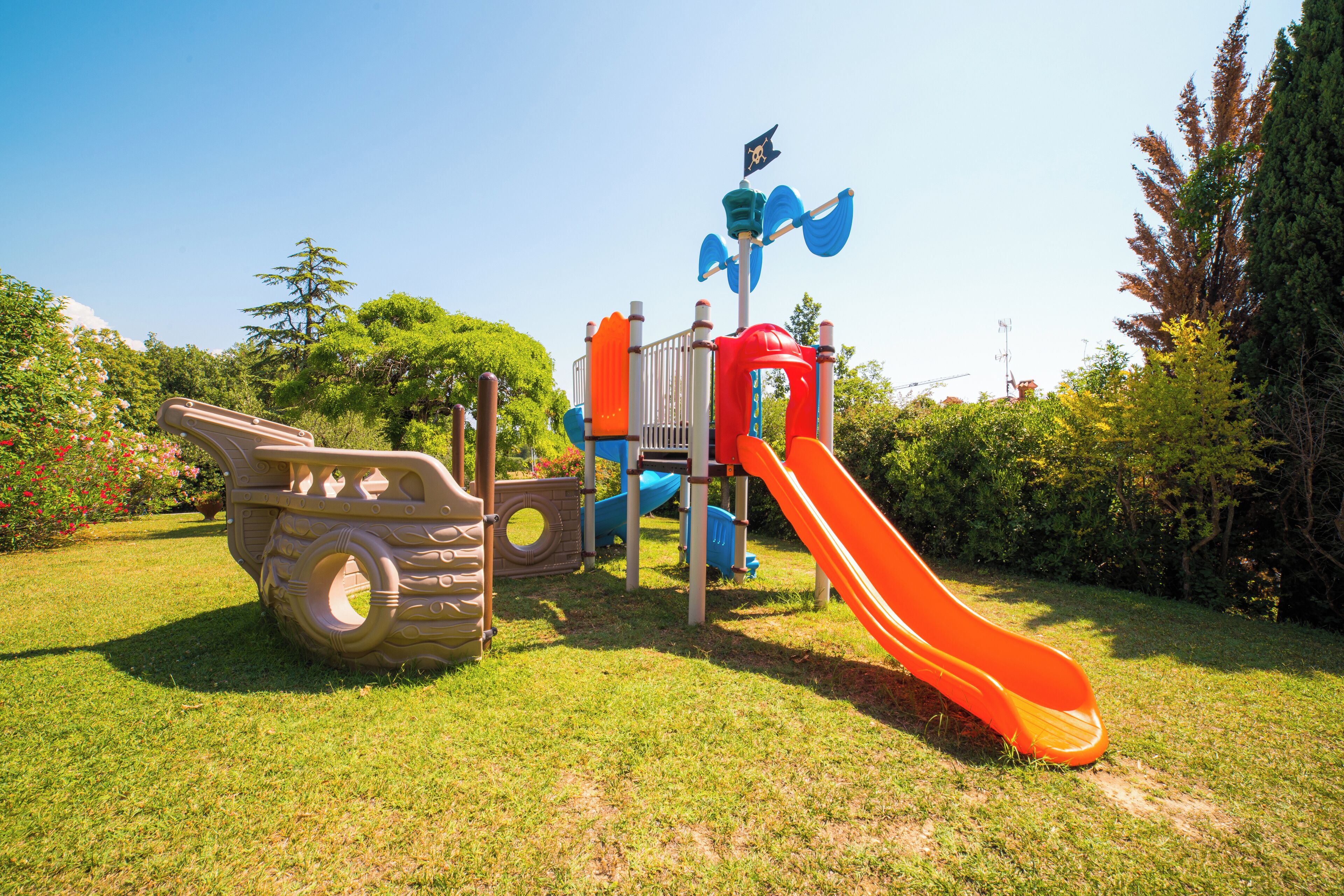 A playground with a slide, climbing structures, and a tire-shaped play area.