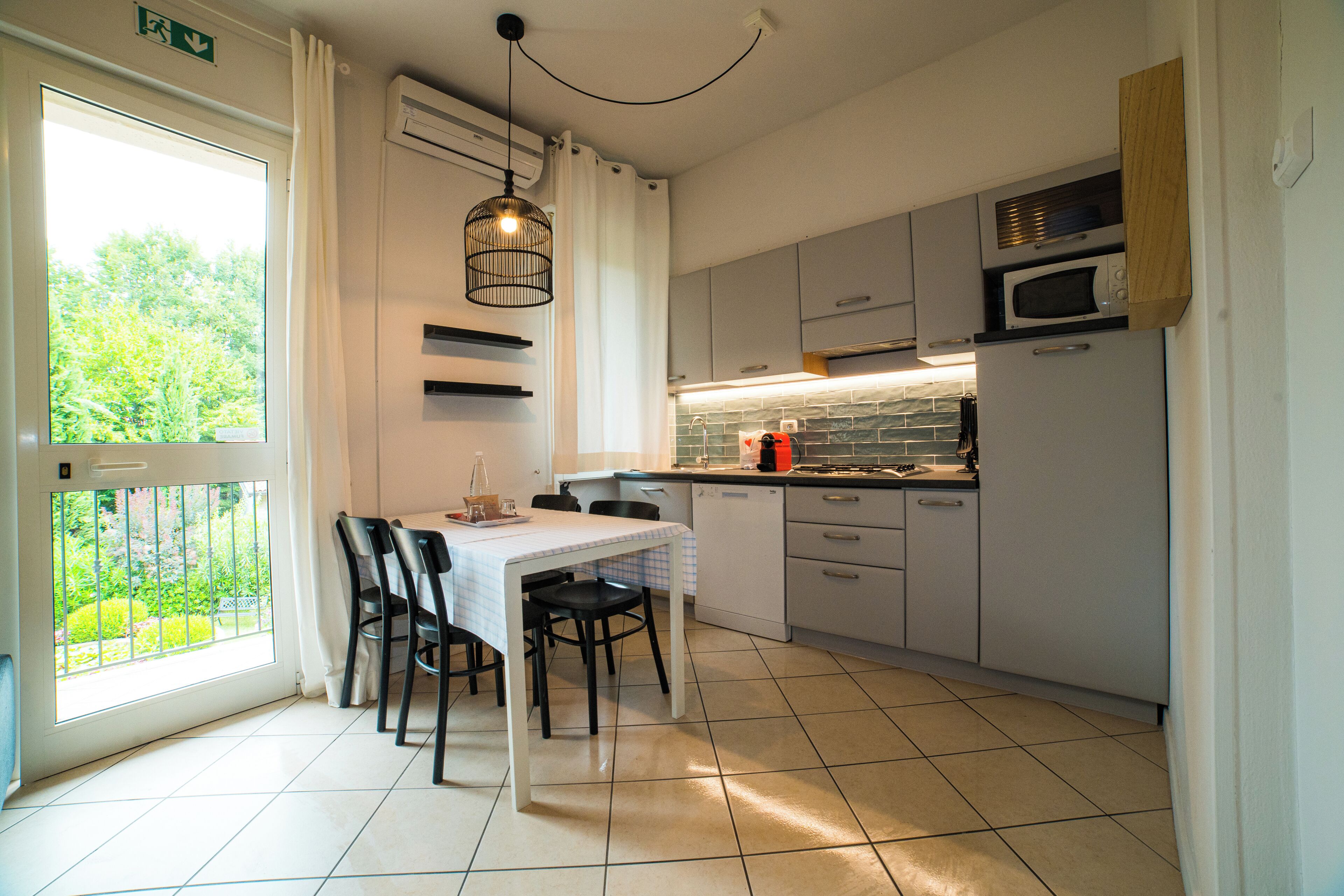 Een moderne keuken met een eettafel, stoelen en uitzicht op groen.