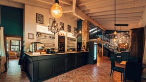 Un grand espace bar doté d’un parquet en chevrons, de meubles en bois foncé et de diverses bouteilles et verres exposés sur des étagères.