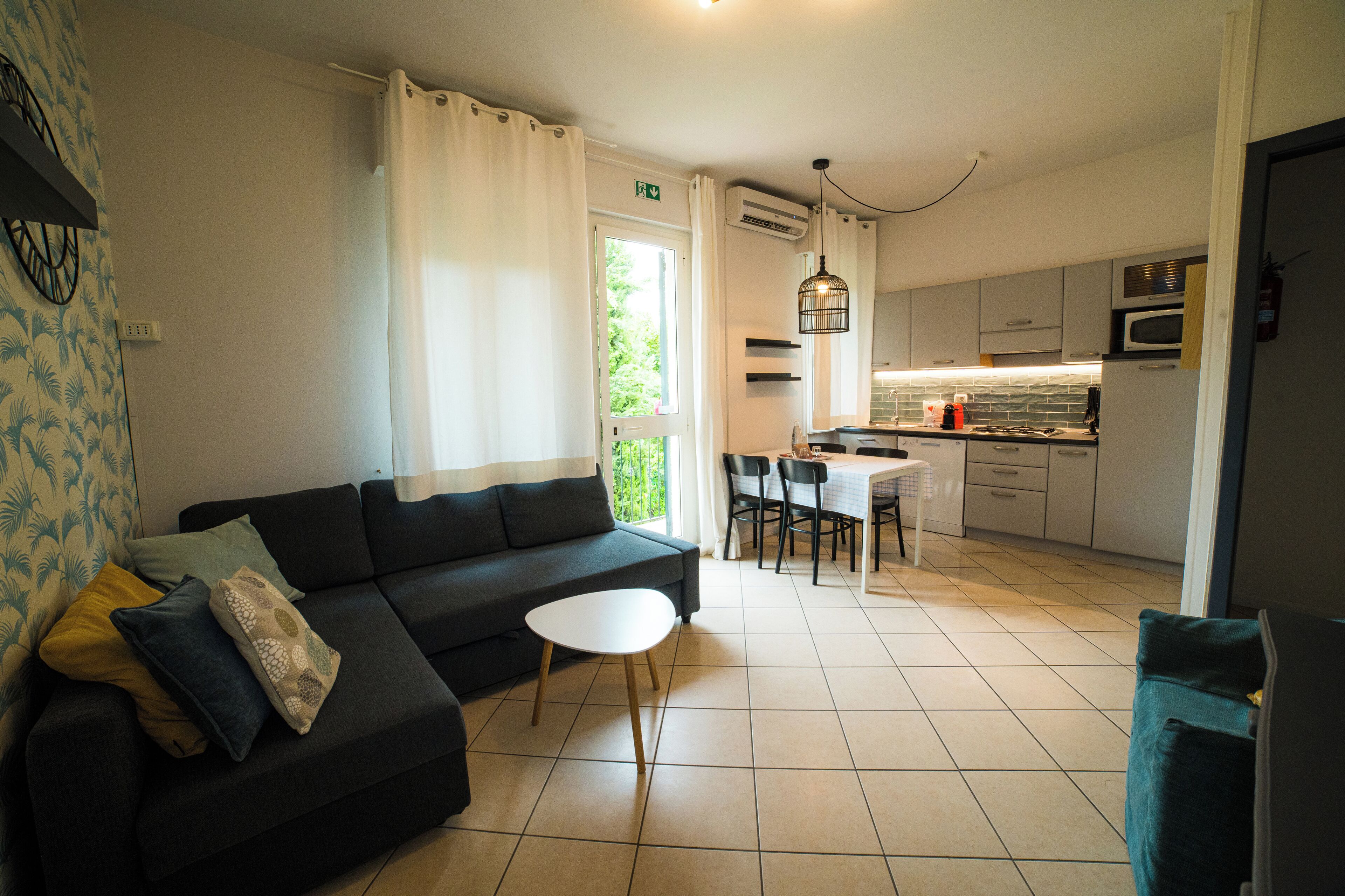 A modern living room with a sofa, a small round table, and a dining area with chairs.