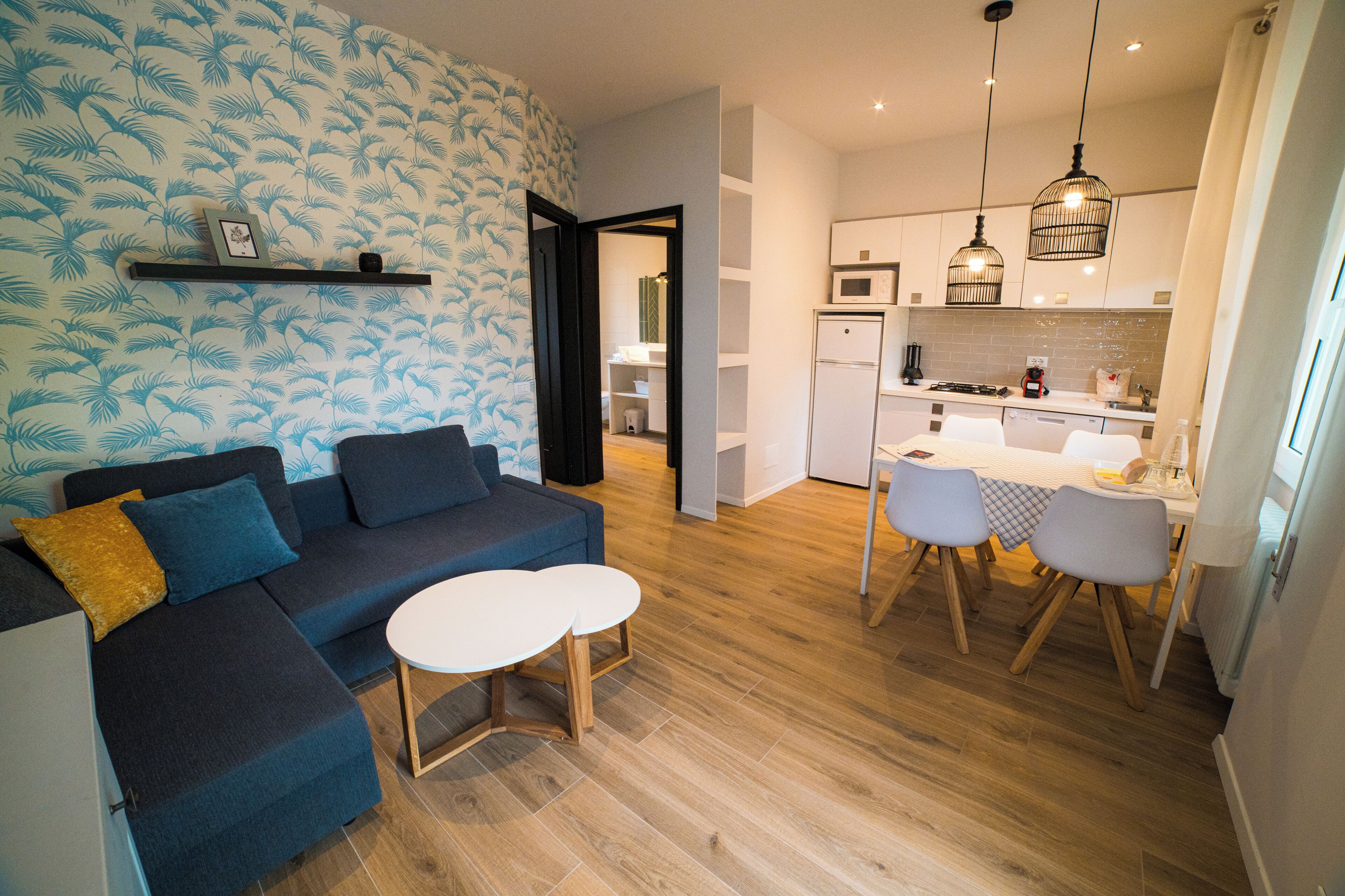 Una sala de estar moderna con un sofá azul oscuro, una mesa de centro blanca y un papel tapiz estampado.