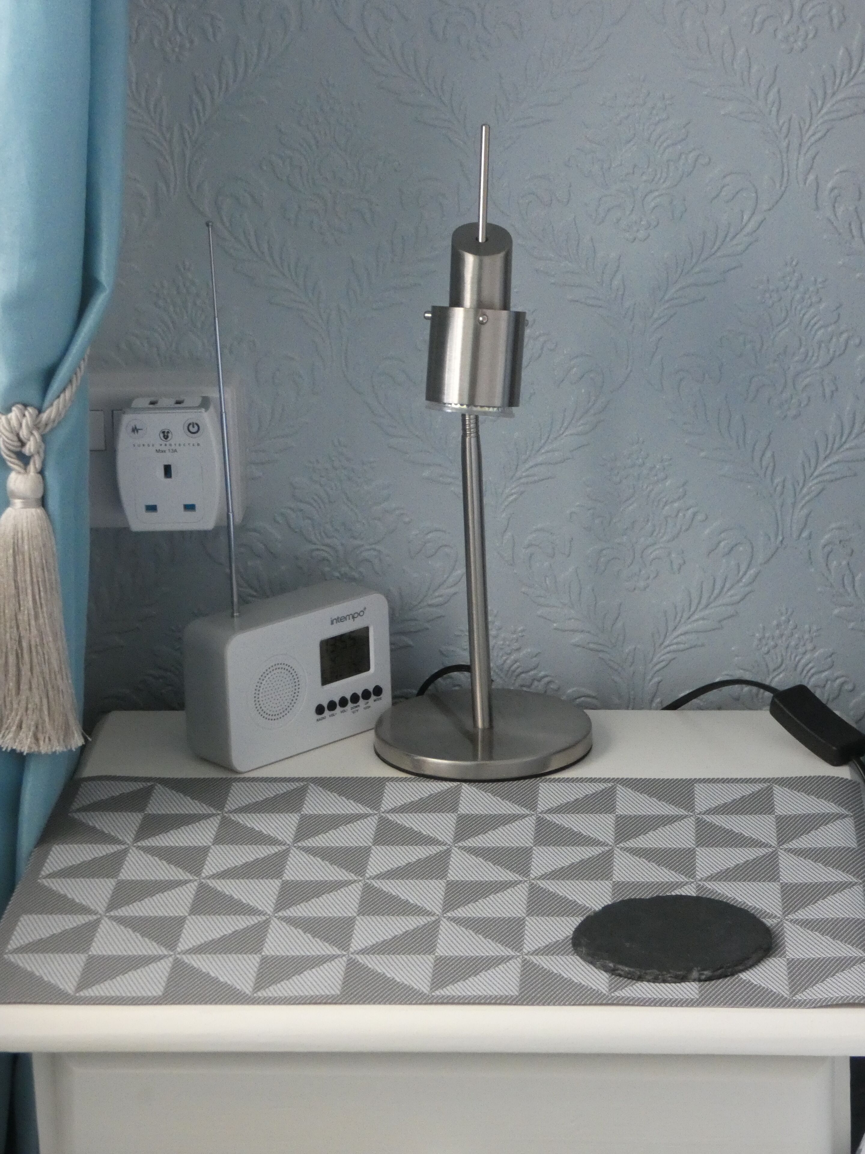 A bedside table with a radio, a lamp, and a power strip.