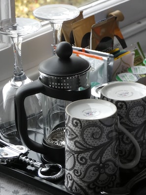 Un comptoir de cuisine avec une machine à café, deux tasses à motifs et une carafe en verre.